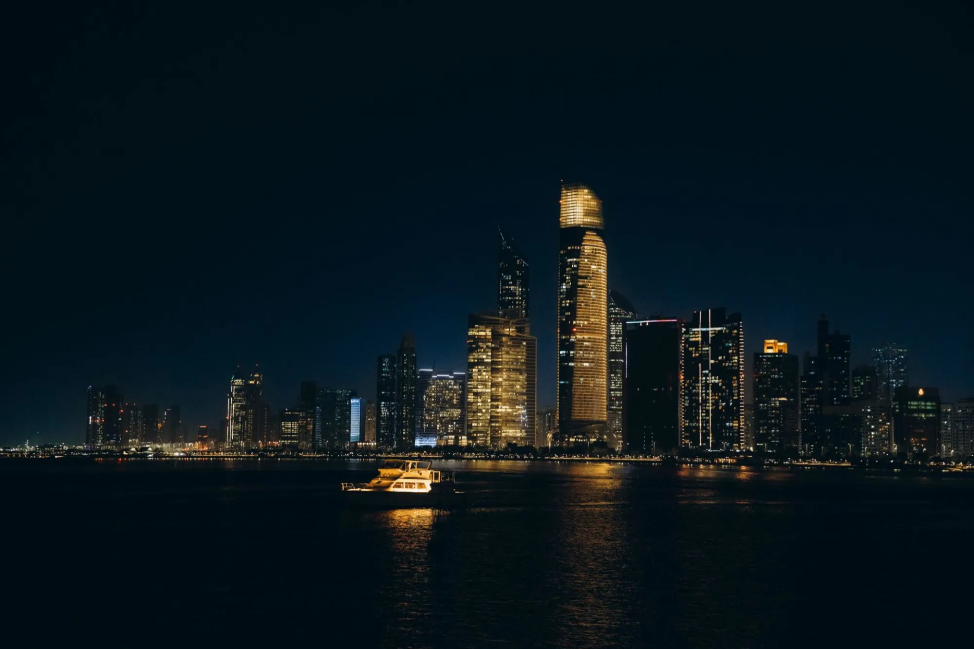 Abu Dhabi towers lit up at night above the water