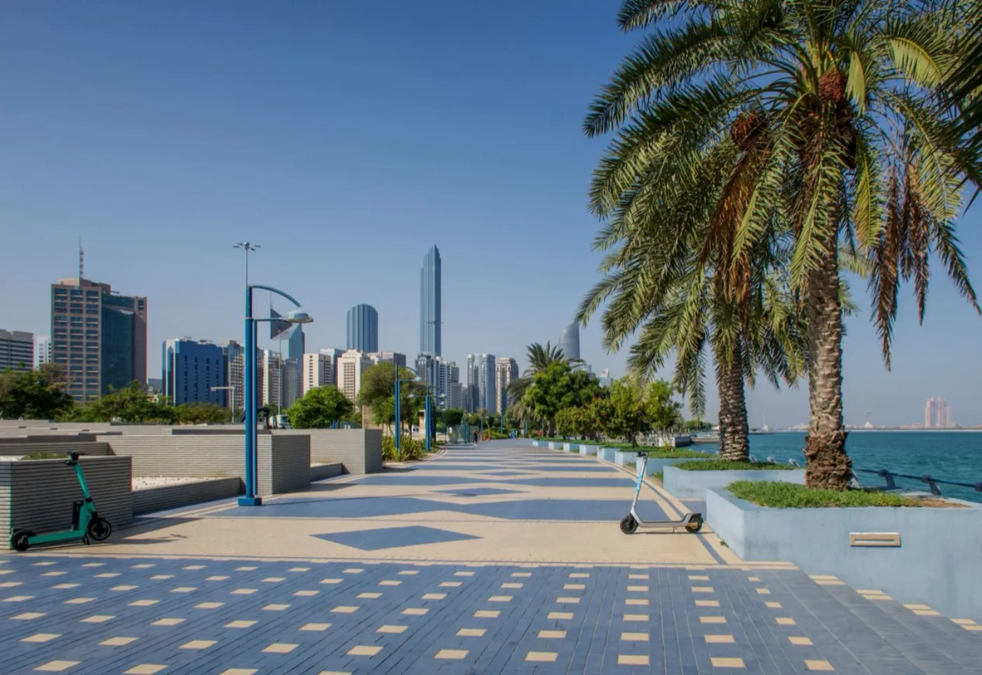 Palm-lined waterfront promenade in Abu Dhabi with towers behind